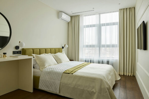 Bedroom with wood floor, plush bed with headboard, and large window.