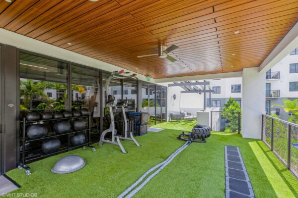 Indoor/outdoor fitness area with calisthenics equipment and turf.