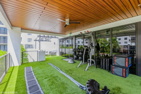 Indoor/outdoor fitness area with calisthenics equipment and turf.