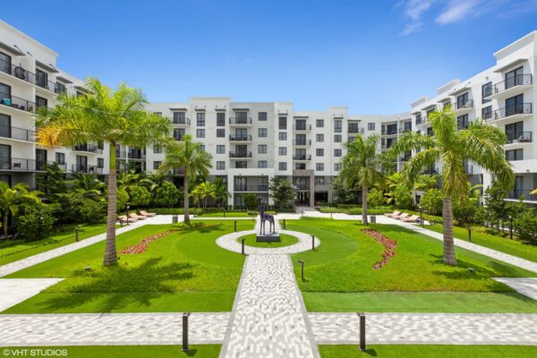 Apartment courtyard with paver paths, tall palm trees, and giraffe sculpture.