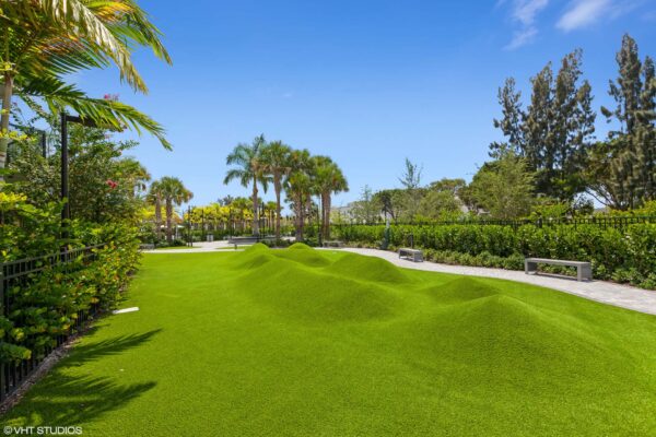 Outdoor courtyard with lush green lawns and paver paths with benches.