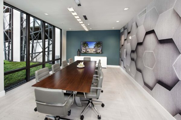 Business center with large table, office chairs, and wall mounted TV.