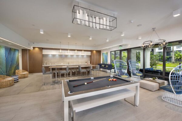 Game room with billiards table, community kitchen and lounge, and large windows.