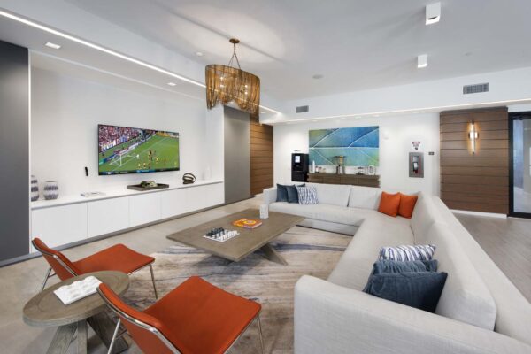 Media lounge with plush seating, coffee table with chess set, and wall mounted TV.