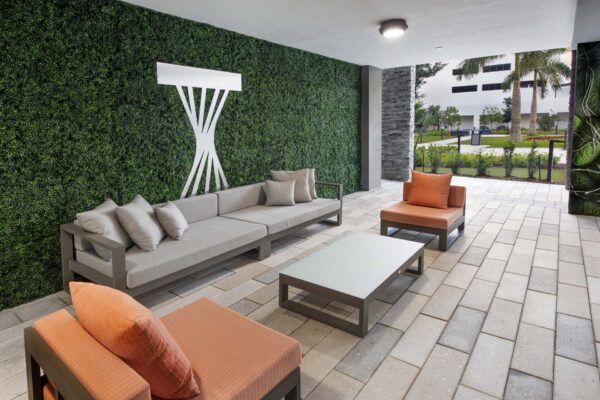 Outdoor lounge with stone paver patio, plush seating, and plant wall.