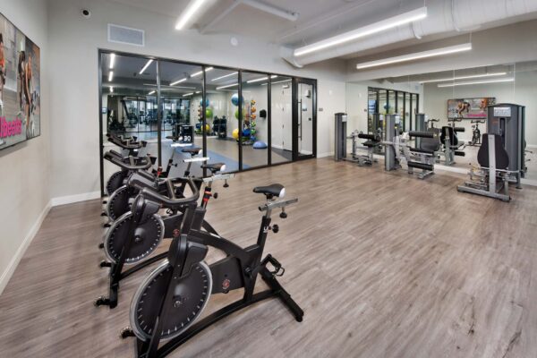 Fitness center with wood style floor, cardio machines, and weight equipment.