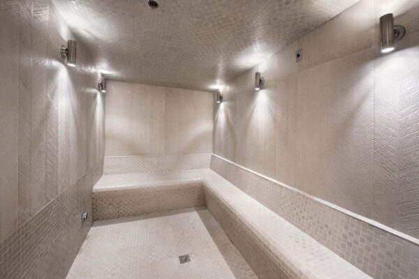 Steam room with tiled walls and benches.