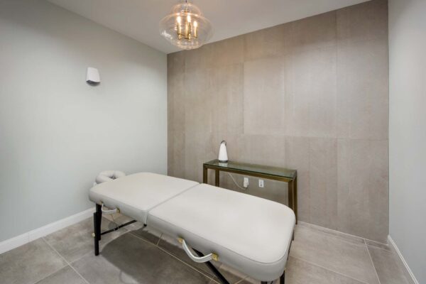 Treatment room with massage table and soft lamp.
