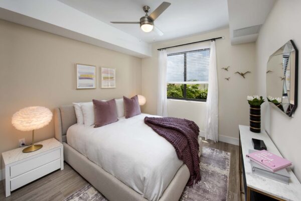 Bedroom with plush bed, bedside tables with lamps, and large windows.