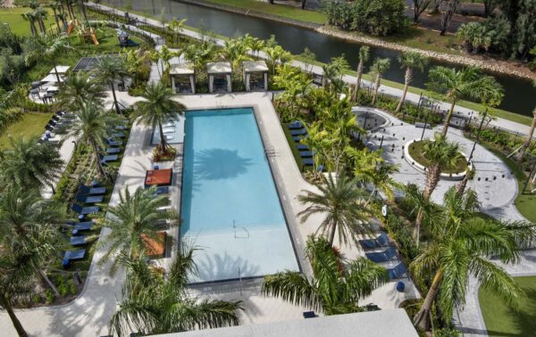 Aerial view of pool area with lounge chairs and palm trees.