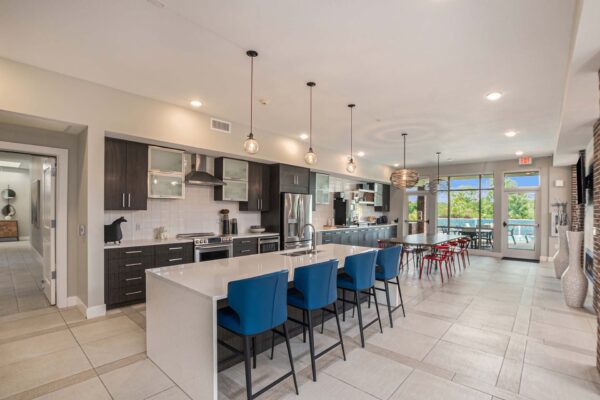 Community kitchen with dining tables, tiled floors, and stainless steel appliances.
