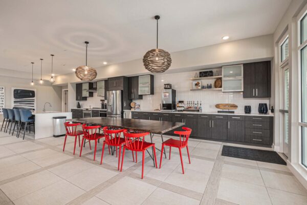 Community kitchen with dining tables, tiled floors, and stainless steel appliances.