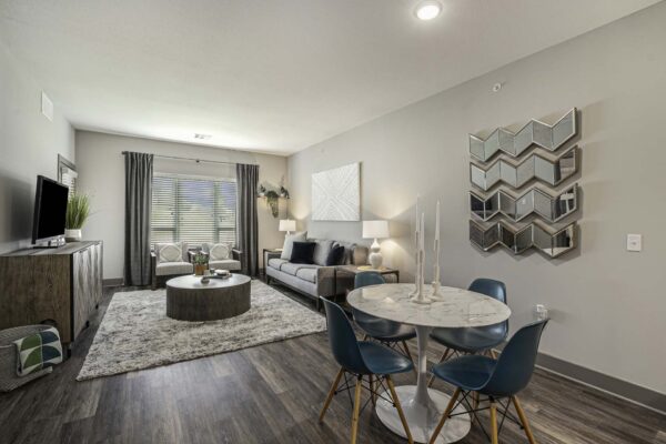 Apartment living area with wood style floors, dining table, and seating area with plush chairs.
