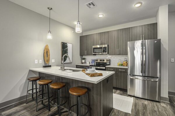 Kitchen with wood style floor and cabinets, light counters, and stainless steel appliances.