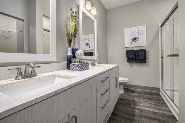 Bathroom with wood style floor and cabinets, light counters, and tiled shower.