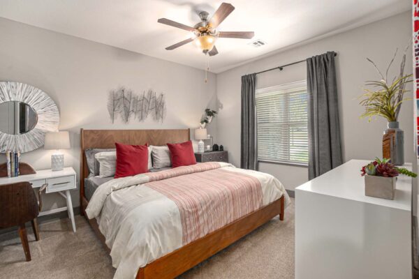 Bedroom with carpet, plush bed with pillows, dressing table with mirror, and large window.