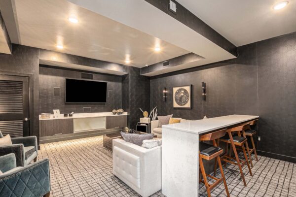 Lounge with pattern carpets, plush seating, and wall mounted TV.