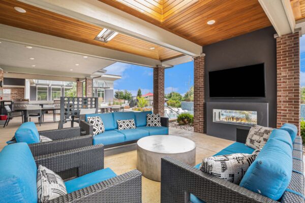 Outdoor lounge with plush seating, fireplace, wall mounted TV, and outdoor games.