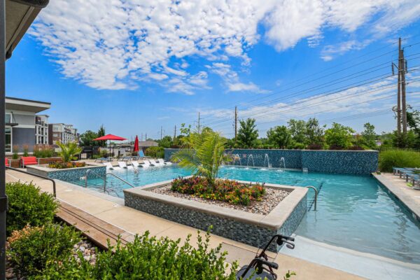 Pool area with lounge chairs, umbrellas, and lush planters.