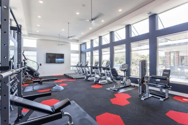 Fitness center with weight lifting equipment, cardio machines, and large windows.