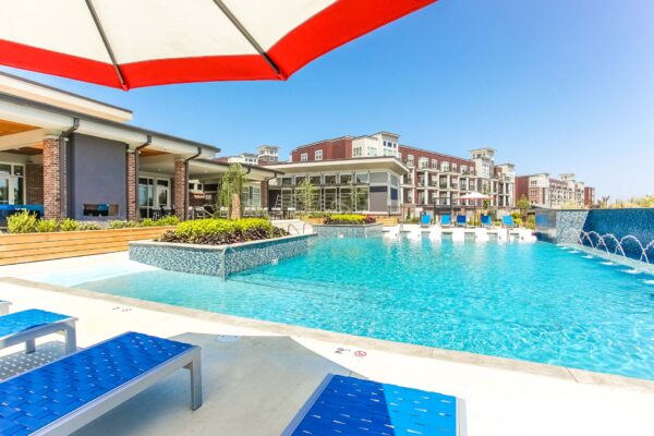 Pool area with lounge chairs, umbrellas, and lush planters.