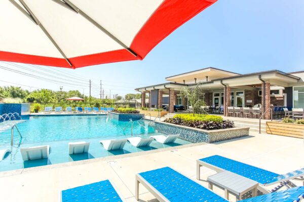 Pool area with lounge chairs, umbrellas, and lush planters.