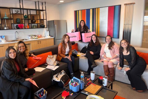 Avanti employees sitting on couch together with Crumbl cookies.