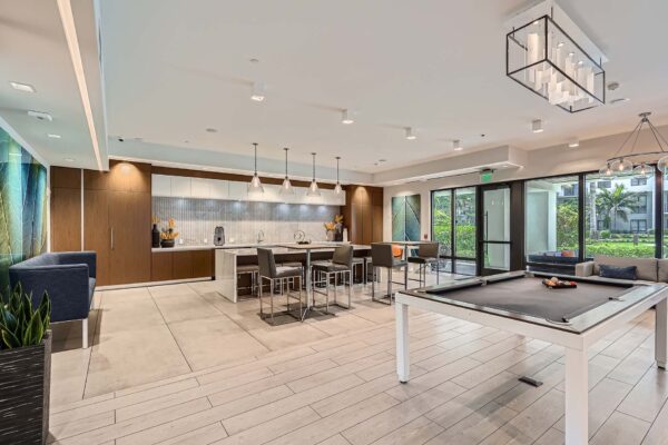 Sanctuary Doral apartments clubroom with billiards, community kitchen, and dining tables.