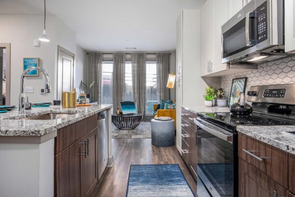 Arte KC apartment kitchen with wood style floor and cabinets, stone counters, and stainless steel appliances.