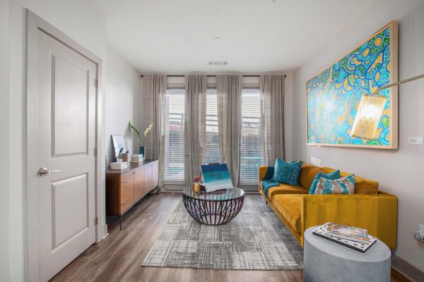 Arte KC apartment living room with wood style flooring, plush seating, and colorful framed artwork.