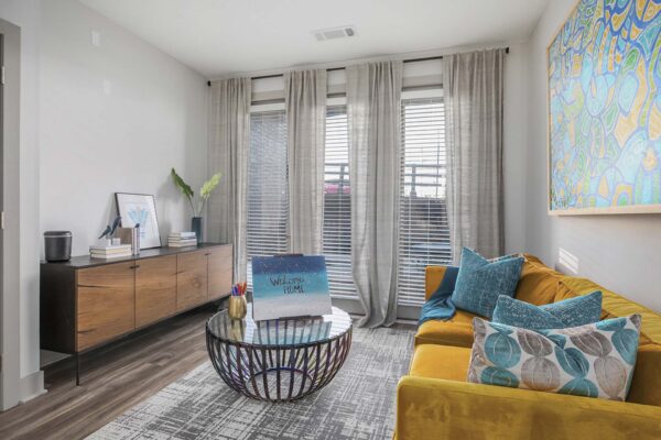 Arte KC apartment living room with wood style flooring, plush seating, and colorful framed artwork.