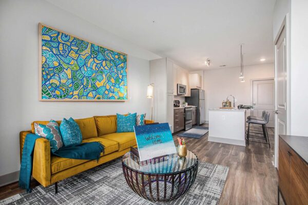 Arte KC apartment living room with wood style flooring, plush seating, and colorful framed artwork.