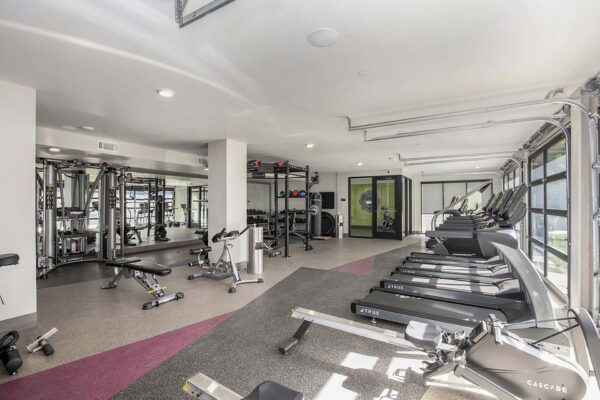 Arte KC apartments fitness center with cardio machines, weight equipment, and garage doors.