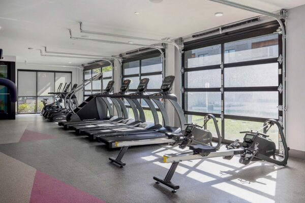 Arte KC fitness center with cardio machines and garage doors.