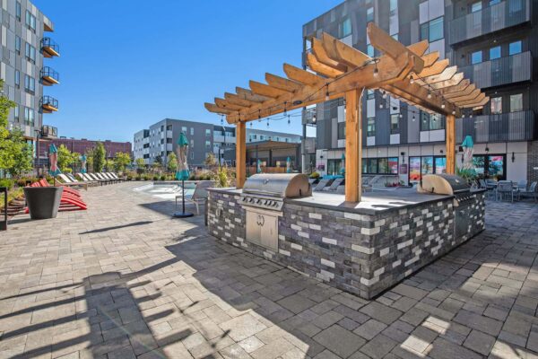 Arte KC pool area with stone paver patio, built in BBQ grills, and colorful lounge chairs.