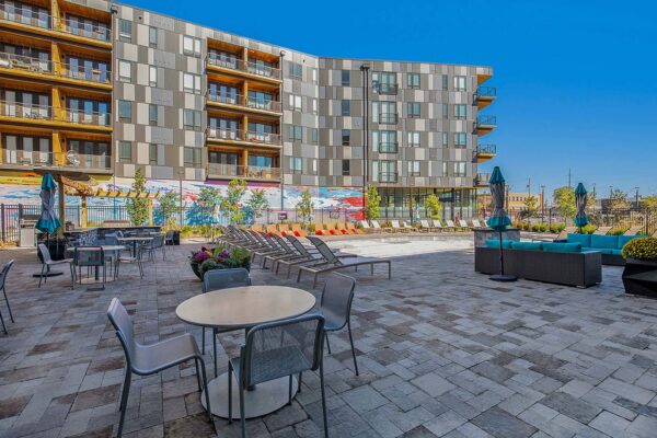 Arte KC pool area with stone paver patio, lounge chairs, and colorful mural.
