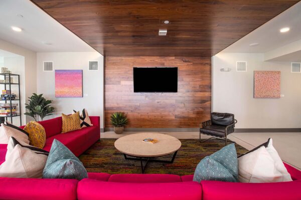 Lounge at Arte KC apartments with plush pink couch, colorful artwork, and large TV.