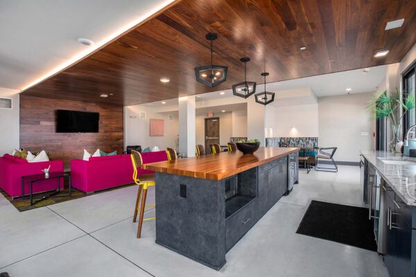 Arte KC community kitchen with large dining bar, colorful stools, and plush seating area with TV.