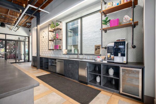 Arte KC community kitchen with dark counters and cabinets, stainless steel appliances, and shelves with decor.