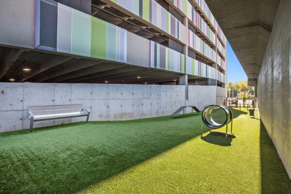 Dog run at Arte KC apartments with benches, agility structures, and artificial turf.