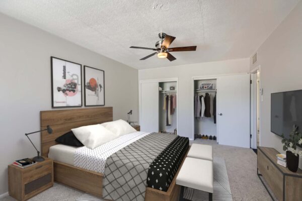 Aura at Midtown apartment bedroom with wood bed frame, artwork, and dual closets.