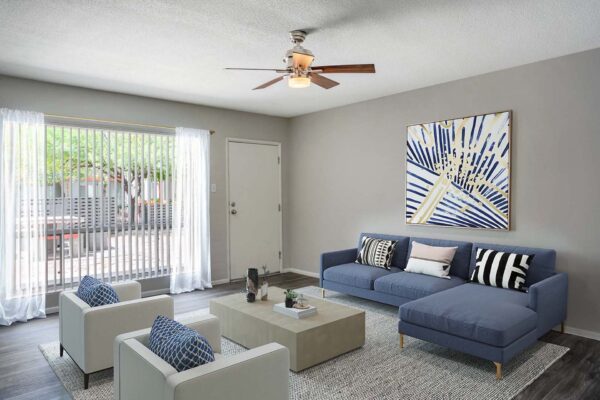 Aura at Midtown apartment living room with plush seating, framed artwork, and large window.