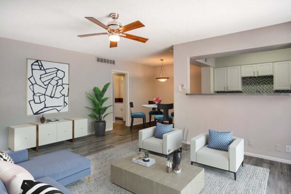 Aura at Midtown apartment living room with plush seating, large artwork, and ceiling fan.