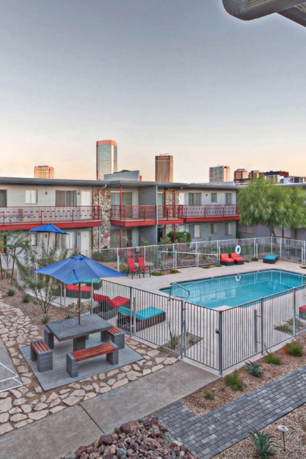 Aura at Midtown apartments pool area with lounge chairs, metal fence, and stone patio.