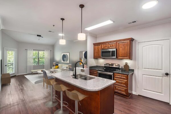 Highlands Lodge apartment kitchen with wood style floor and cabinets, stone counters, and stainless steel appliances.