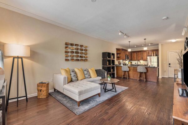 Highlands Lodge apartment living room with wood style floor, plush seating, and elegant kitchen.