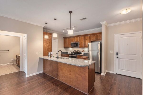 Highlands Lodge apartment kitchen with wood style floor and cabinets, dark stone counters, and stainless steel appliances.