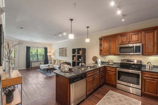 Highlands Lodge apartment kitchen with wood style floor and cabinets, dark stone counters, and stainless steel appliances.