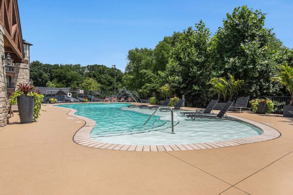 Highlands Lodge apartments pool area with lounge chairs, fountains, and lush landscaping.