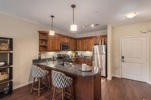 Highlands Lodge apartment kitchen with wood style floor, stone counters, stainless steel appliances, and breakfast bar.